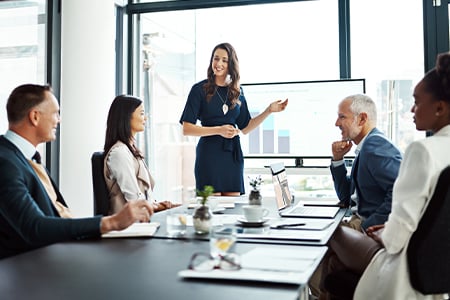 Woman leading business meeting with team seated at conference table