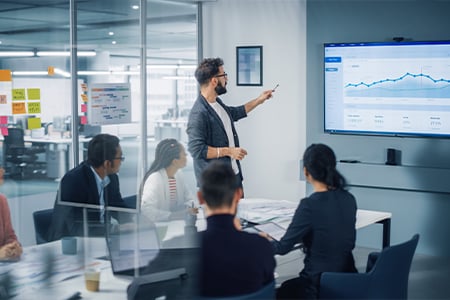 Business professional presenting data chart to team in conference room