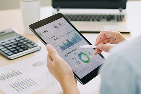 Person reviewing financial dashboard on tablet at desk