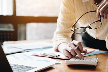 Professional reviewing financial reports with calculator and laptop