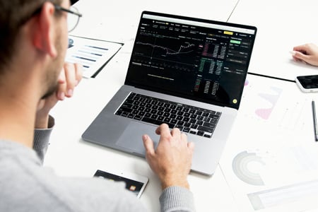 Person analyzing trading charts on laptop at workspace