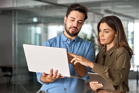 Two colleagues reviewing information on laptop in office