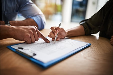 Business professionals reviewing and signing documents at table